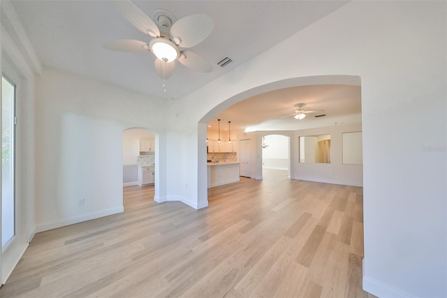 unfurnished living room with a healthy amount of sunlight, light wood-type flooring, and ceiling fan