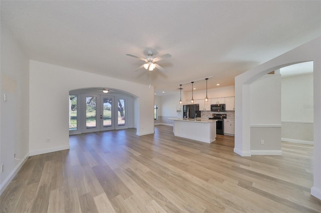 unfurnished living room with french doors, light hardwood / wood-style floors, sink, and ceiling fan