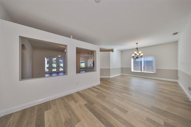 empty room featuring french doors, hardwood / wood-style flooring, and an inviting chandelier