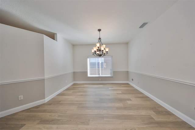 unfurnished dining area with a notable chandelier and light wood-type flooring