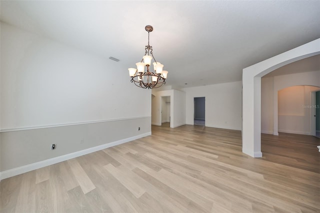 unfurnished living room with a chandelier and light wood-type flooring