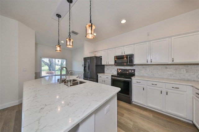 kitchen with appliances with stainless steel finishes, wood-type flooring, white cabinets, and an island with sink