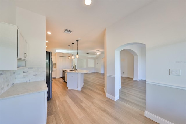 kitchen featuring white cabinets, hanging light fixtures, a center island with sink, light hardwood / wood-style floors, and sink