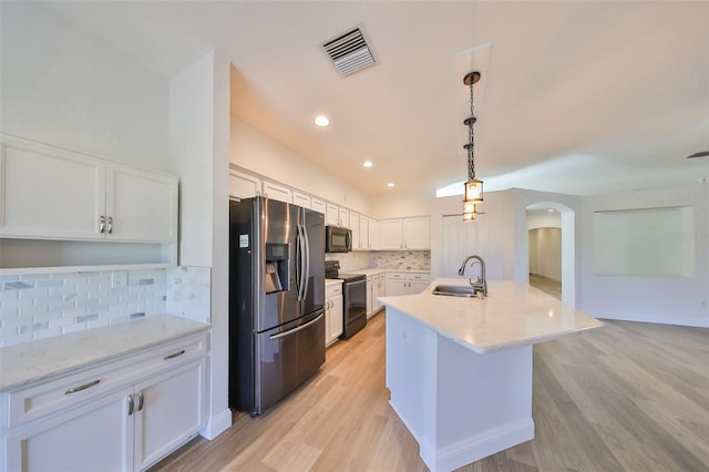 kitchen with a center island with sink, sink, white cabinets, decorative light fixtures, and appliances with stainless steel finishes