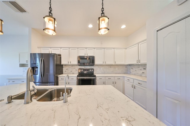 kitchen featuring appliances with stainless steel finishes, pendant lighting, white cabinetry, and tasteful backsplash