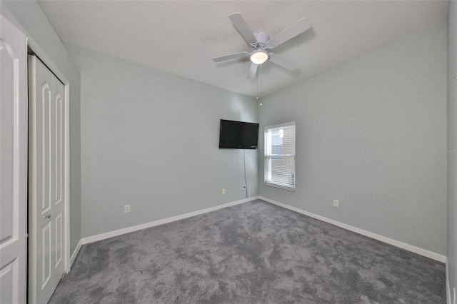 unfurnished bedroom with a closet, dark carpet, and ceiling fan