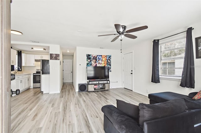 living room with sink, light wood-type flooring, and ceiling fan