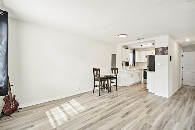 kitchen with stainless steel fridge, sink, white cabinets, and light hardwood / wood-style flooring