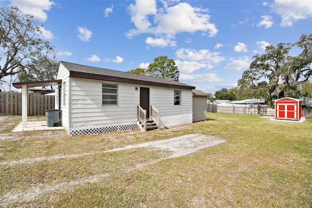 rear view of house with a yard, a pergola, and a storage unit