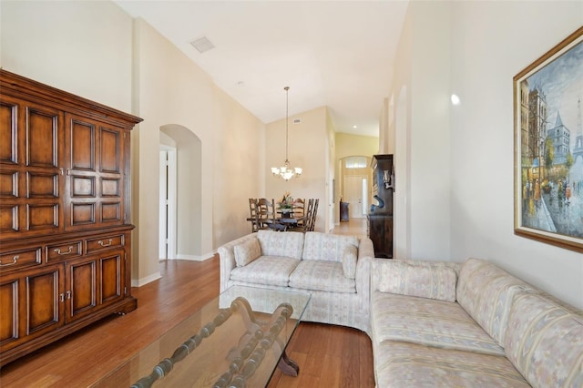 living room with high vaulted ceiling, wood-type flooring, and an inviting chandelier