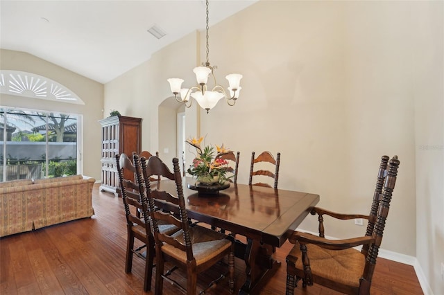 dining area with dark wood-type flooring, vaulted ceiling, and a notable chandelier