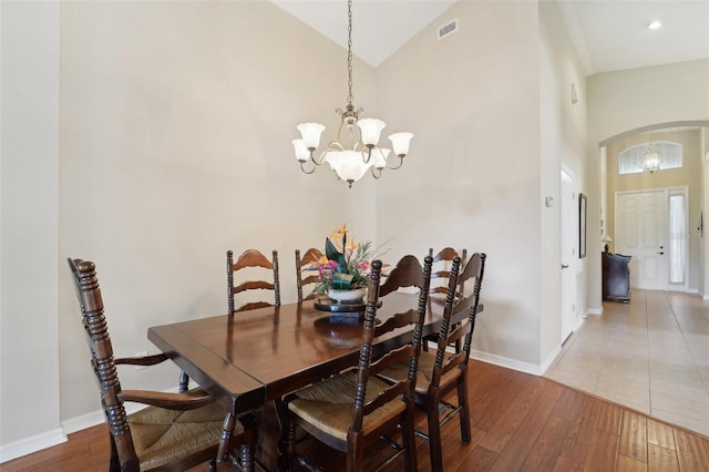 dining area with a notable chandelier, high vaulted ceiling, and wood-type flooring