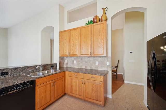 kitchen with black appliances, sink, dark stone counters, and light tile patterned floors