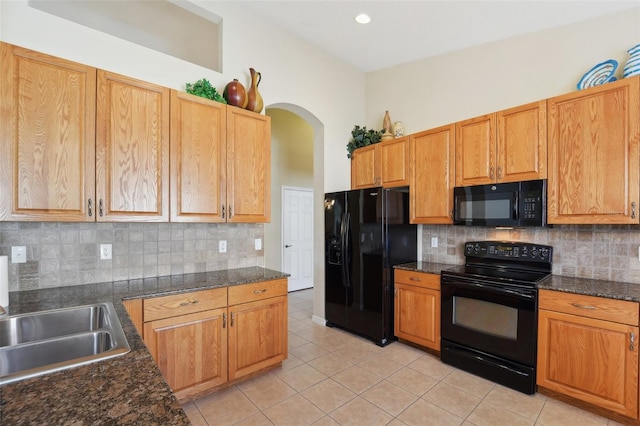 kitchen with black appliances, sink, light tile patterned flooring, dark stone countertops, and decorative backsplash