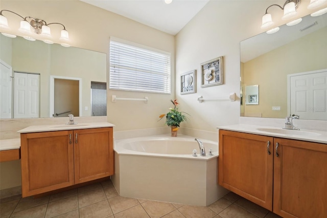 bathroom with vanity, a tub, vaulted ceiling, and tile patterned flooring