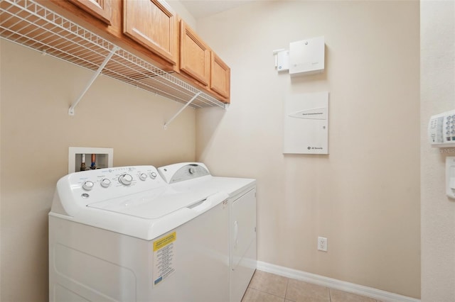 laundry area with cabinets, washing machine and clothes dryer, and light tile patterned floors