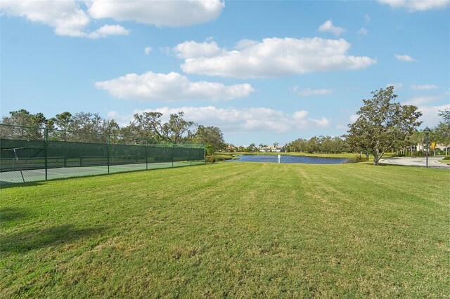 view of yard with a water view and tennis court