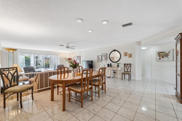 tiled dining room featuring a textured ceiling and ceiling fan