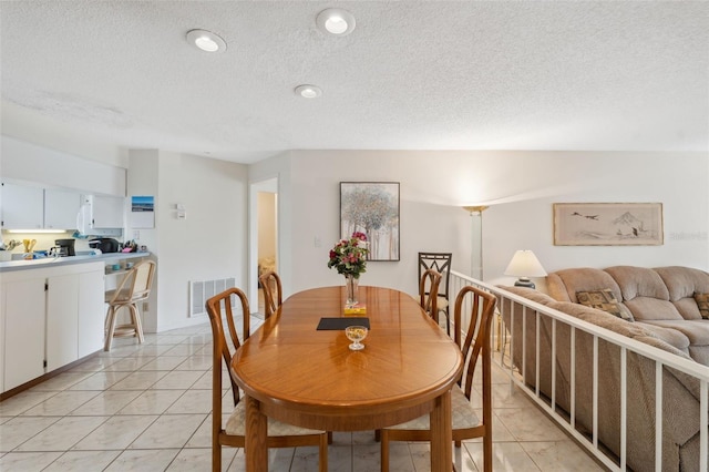 dining space featuring a textured ceiling and light tile patterned floors