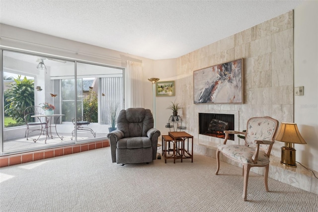 sitting room with a tile fireplace, a textured ceiling, and carpet flooring