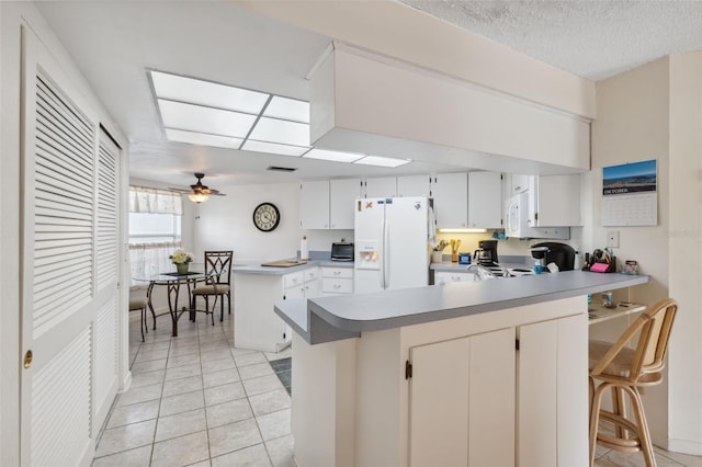 kitchen featuring white cabinetry, kitchen peninsula, white appliances, and a breakfast bar