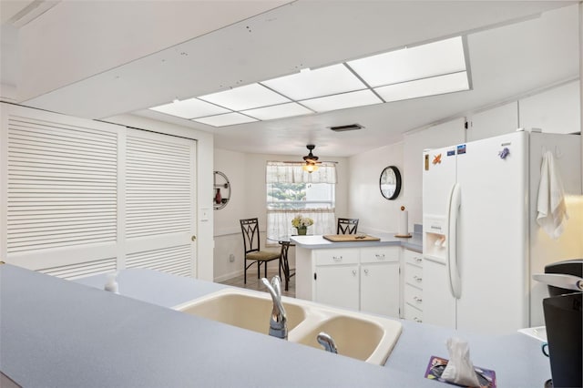 kitchen featuring ceiling fan, kitchen peninsula, white refrigerator with ice dispenser, and white cabinets