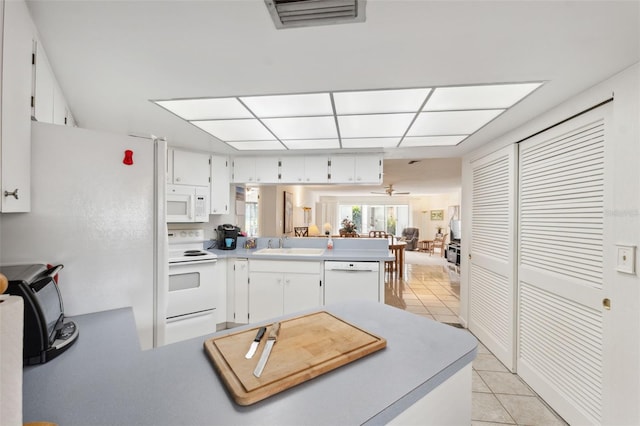 kitchen featuring kitchen peninsula, sink, light tile patterned flooring, white cabinetry, and white appliances