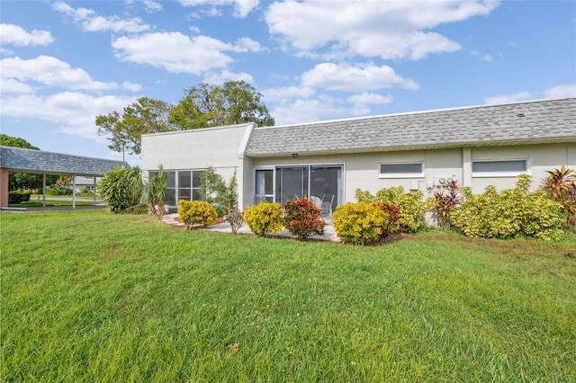 rear view of house featuring a yard and a carport