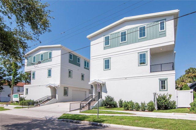 view of front of house featuring an attached garage, fence, stucco siding, and concrete driveway