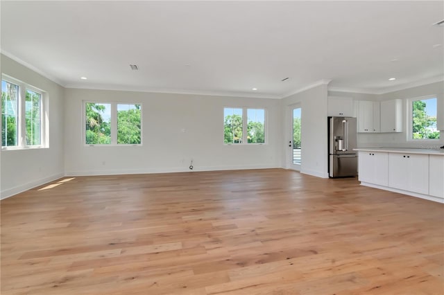 unfurnished living room with crown molding, baseboards, light wood-type flooring, and a healthy amount of sunlight