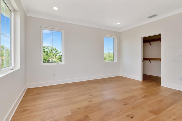 unfurnished bedroom featuring multiple windows, ornamental molding, and light wood-type flooring