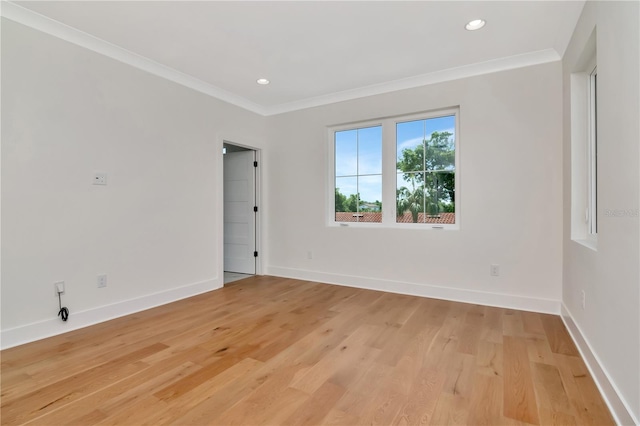 empty room with light wood-type flooring, ornamental molding, and baseboards