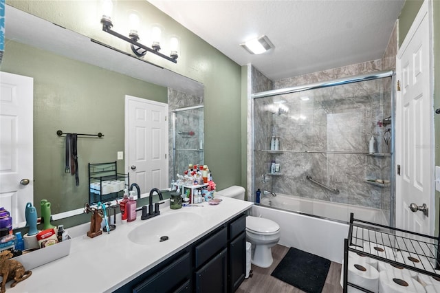 full bathroom with combined bath / shower with glass door, a textured ceiling, vanity, hardwood / wood-style flooring, and toilet