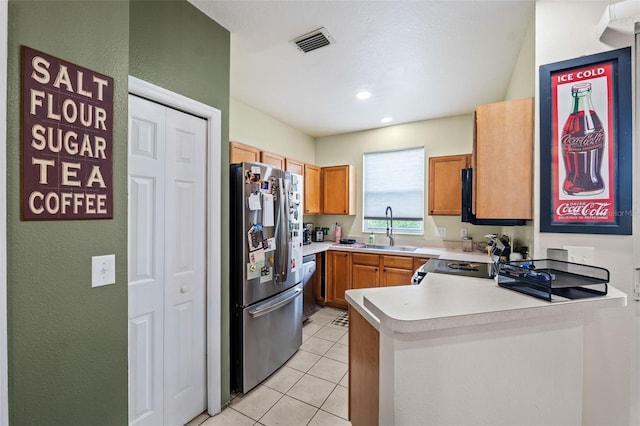 kitchen with kitchen peninsula, stainless steel refrigerator, sink, and light tile patterned flooring