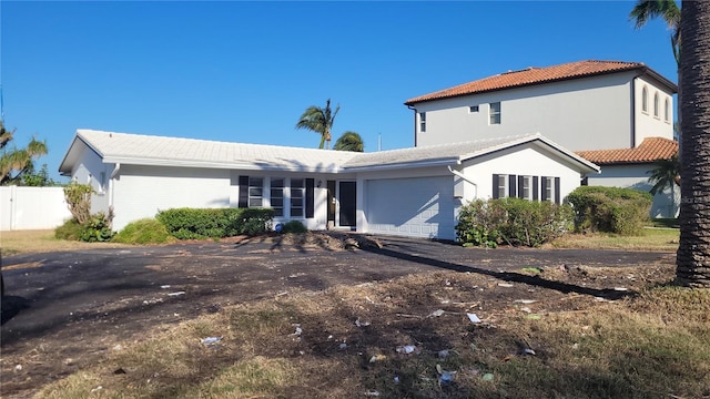 10350 Paradise Blvd, Treasure Island, FL 33706 - view of front facade featuring an attached garage, asphalt driveway, fence, a tiled roof, and stucco siding