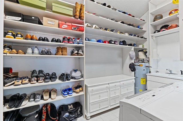 walk in closet featuring washing machine and dryer, water heater, sink, and light tile patterned flooring