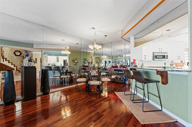 dining space featuring dark wood-type flooring and an inviting chandelier