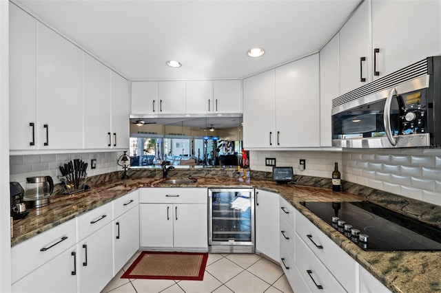 kitchen featuring black electric stovetop, white cabinetry, backsplash, and wine cooler