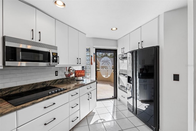 kitchen with dark stone counters, black appliances, white cabinets, decorative backsplash, and light tile patterned floors