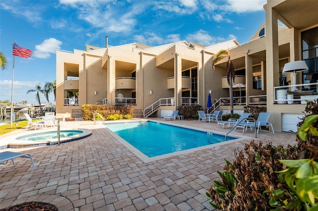 view of pool with a hot tub and a patio area