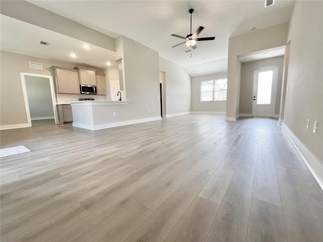 unfurnished living room featuring ceiling fan, lofted ceiling, and light hardwood / wood-style flooring