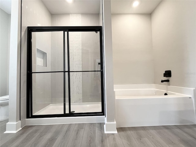 bathroom with toilet, separate shower and tub, and hardwood / wood-style floors