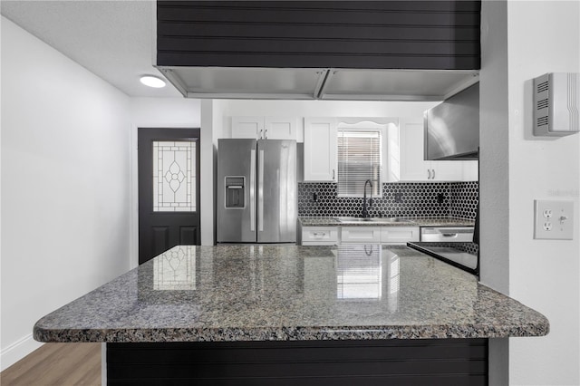 kitchen with stainless steel fridge, backsplash, white cabinetry, light wood-type flooring, and sink