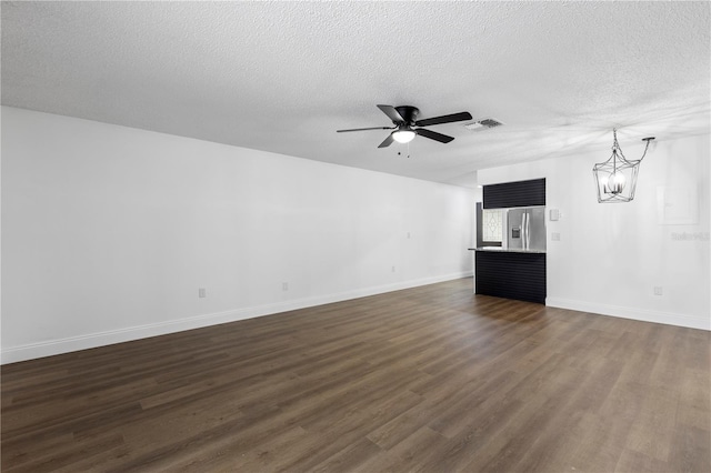 unfurnished living room with dark wood-type flooring, a textured ceiling, and ceiling fan with notable chandelier