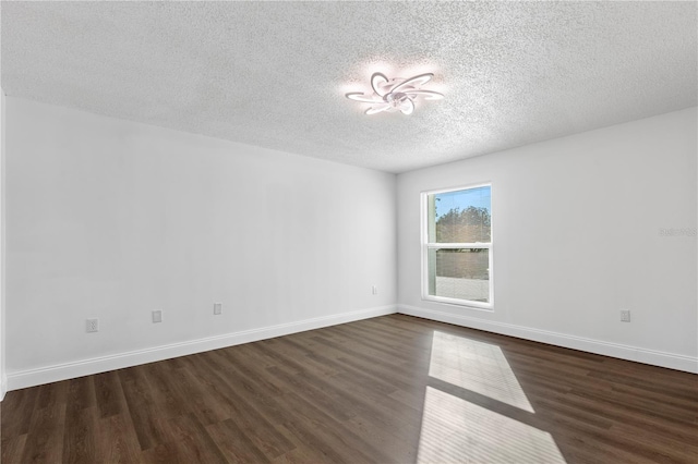 spare room featuring a textured ceiling and dark hardwood / wood-style flooring