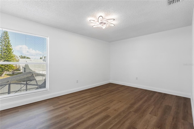 spare room with a textured ceiling and dark hardwood / wood-style floors