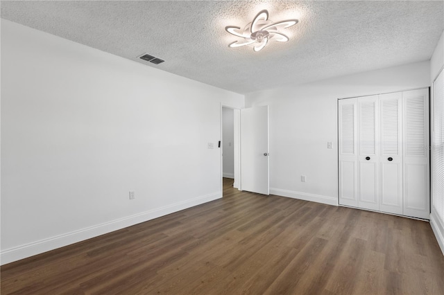 unfurnished bedroom with a closet, a textured ceiling, and dark hardwood / wood-style floors