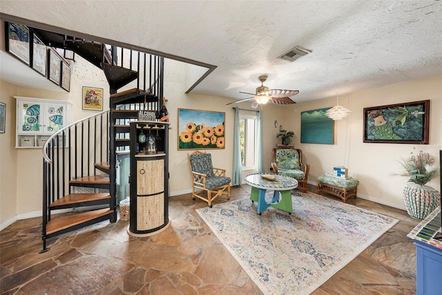 interior space with a textured ceiling and ceiling fan