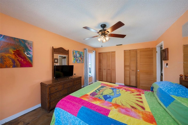 bedroom with two closets, a textured ceiling, and ceiling fan