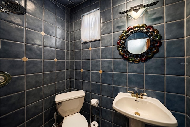 bathroom with toilet, tile walls, and sink